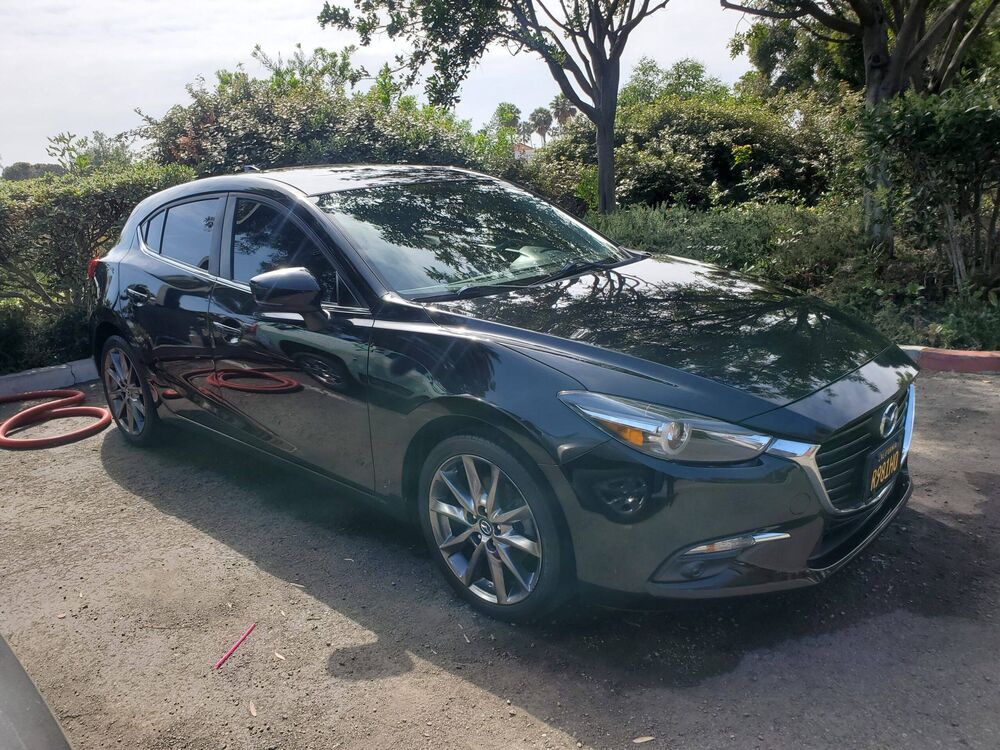 Dark green Mazda3 hatchback detailed on a residential driveway