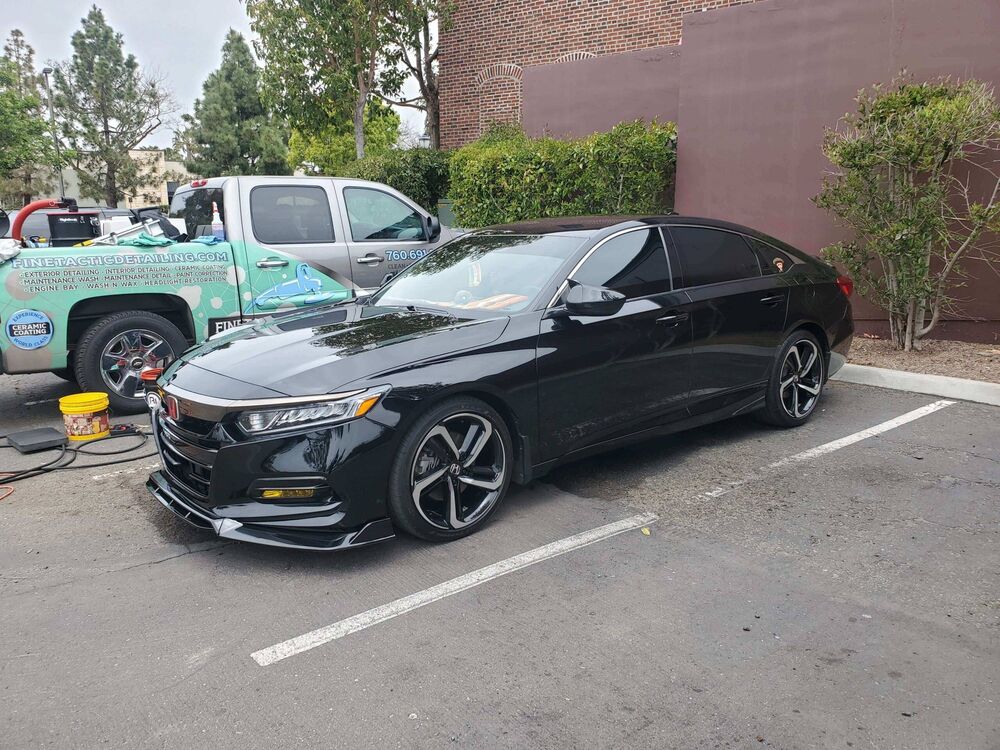 Black Honda Accord detailed in a parking lot, with the Finetactic Detailing truck parked behind it