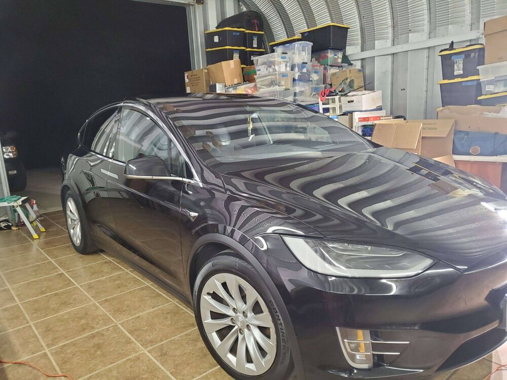 Black Tesla Model X parked in a garage after ceramic coating