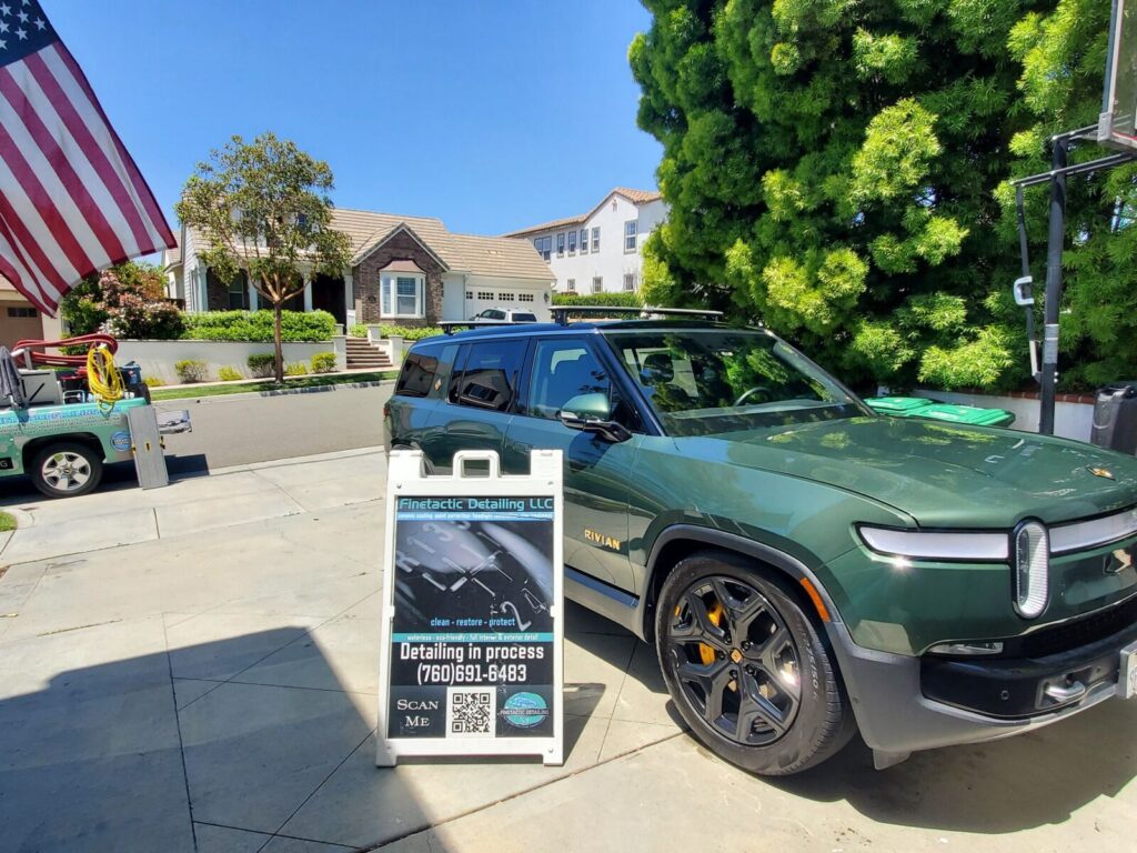 Green Rivian with a Finetactic Detailing sign reading 'Detailing in process'